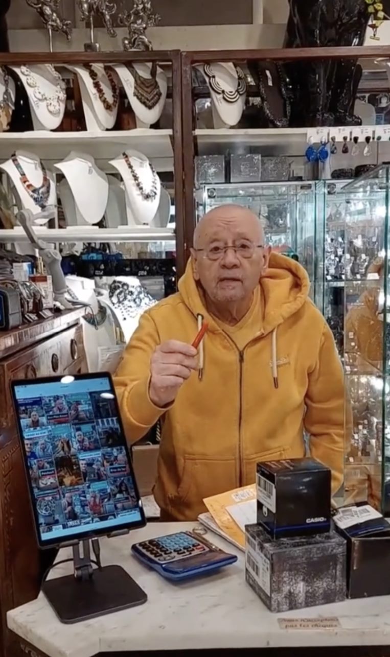 Michel derrière le comptoir de la boutique, tablette de live posée devant lui